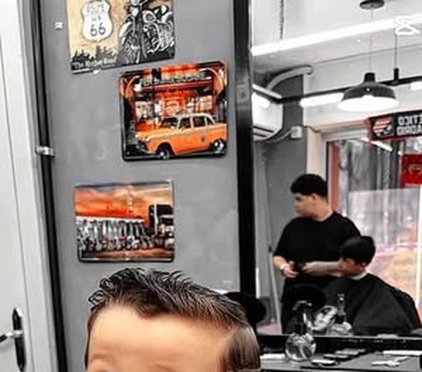 Parede com decoração da barbearia e cliente em atendimento